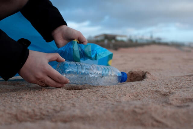 picking up a bottle from the beach